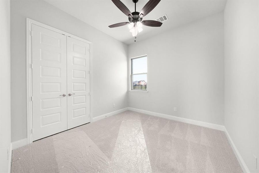 Secondary bedroom featuring carpet flooring, a closet, and ceiling fan