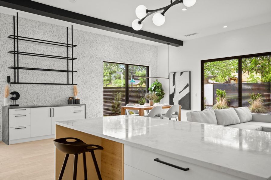 Kitchen with white cabinets, dark stone countertops, a kitchen bar, light wood-style floors, and a chandelier