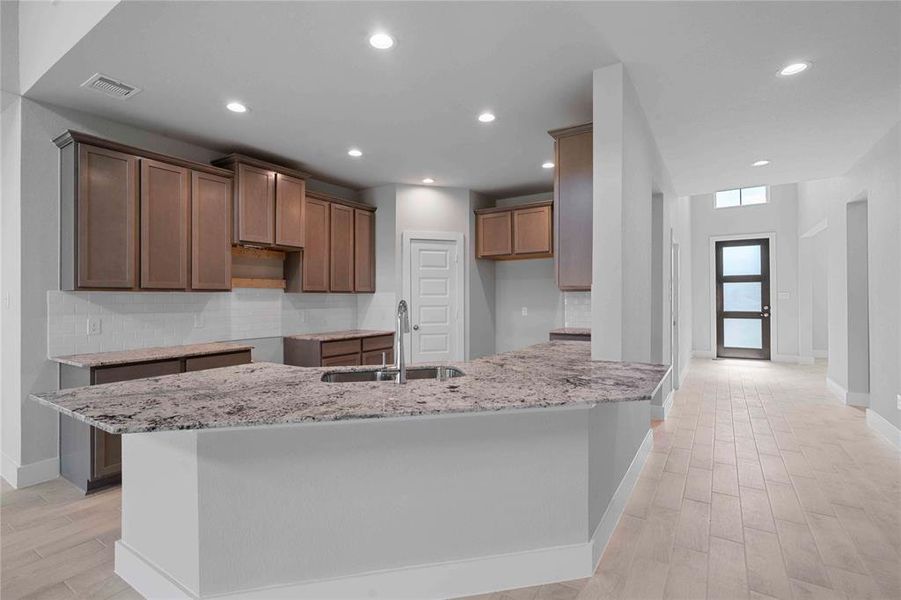 This stunning kitchen displays such beautiful cabinets, custom neutral paint, granite countertops, light modern backsplash, and SS appliances, oversized kitchen with extra storage, breakfast bar, recessed lighting, high ceilings and pantry.