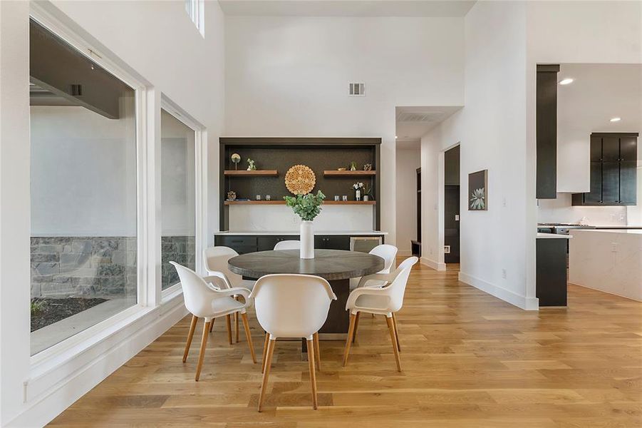 Dining space with light wood-type flooring, a towering ceiling, and a wealth of natural light