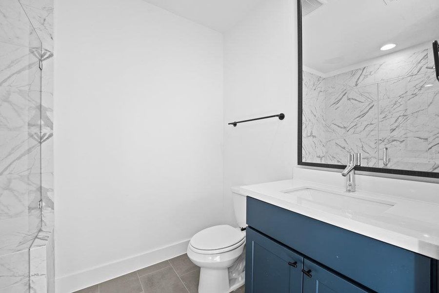 Bathroom featuring vanity, a marble finish shower, tile patterned floors, and recessed lighting
