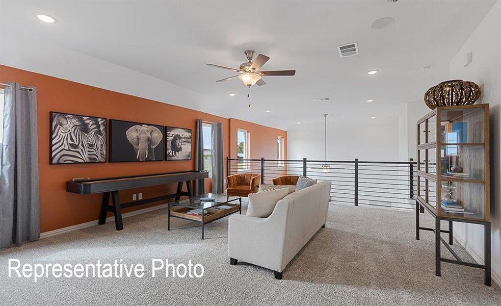 Spacious loft area featuring a modern black metal railing, recessed lighting, and a ceiling fan