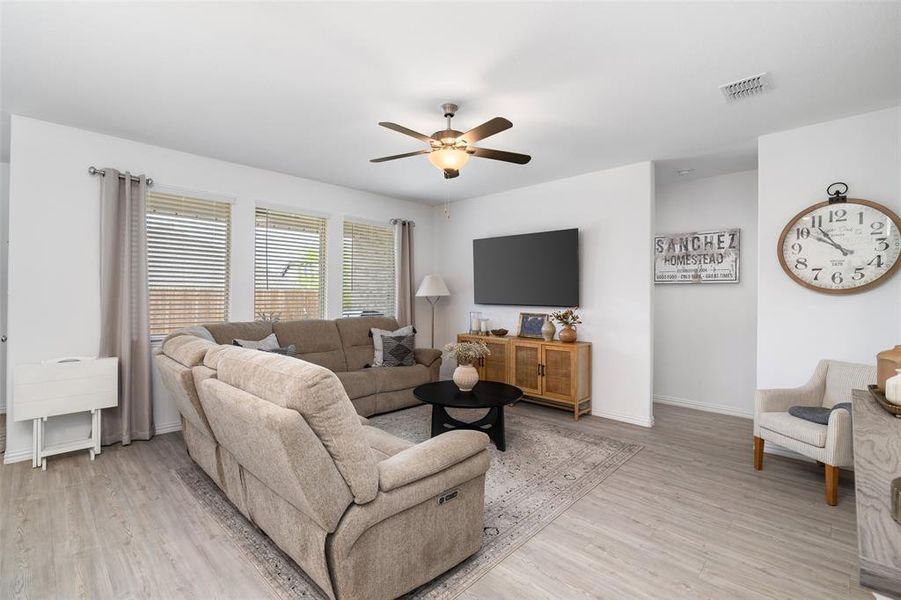 Bright living area featuring light-colored flooring, white walls, and a ceiling fan