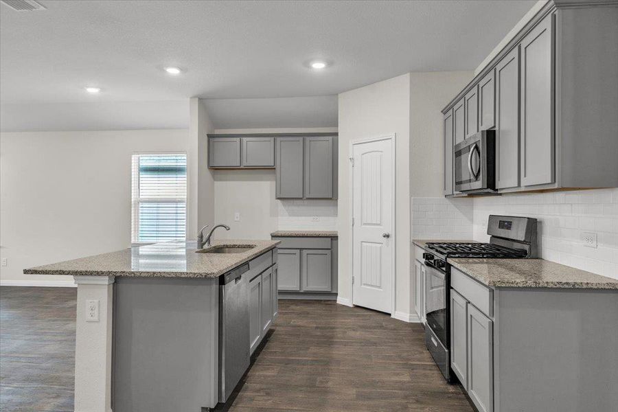 The kitchen features gray cabinetry, granite countertops, and a white subway tile backsplash