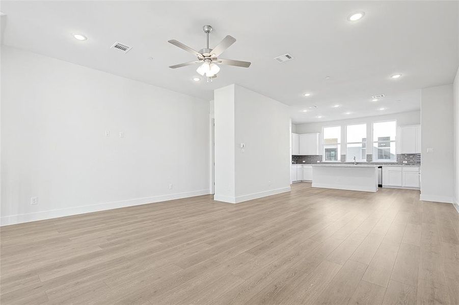 The open concept living area features light-colored flooring, recessed lighting, and a ceiling fan