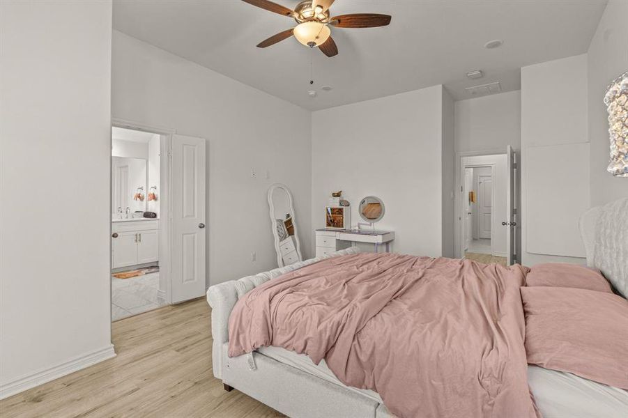 Bedroom featuring light wood-type flooring, ceiling fan, and connected bathroom