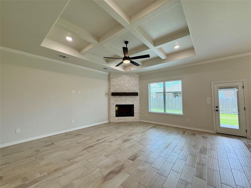 Unfurnished living room featuring coffered ceiling, wood finish floors, beamed ceiling, ceiling fan, and a fireplace