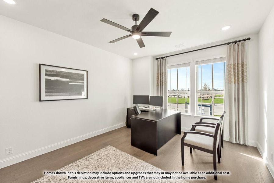 Home office with dark wood desk, ceiling fan, hardwood floors, and large window with outdoor view Home office with dark wood desk, ceiling fan, hardwood floors, and large window with outdoor view