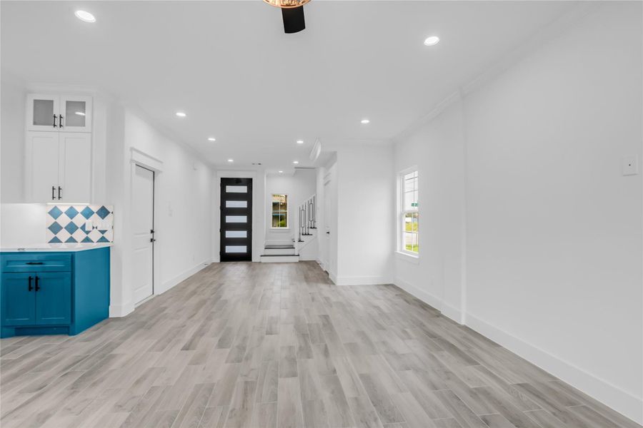 This stylish living room boasts sleek wood flooring, vibrant cabinetry, and a modern open layout, perfect for contemporary living.
