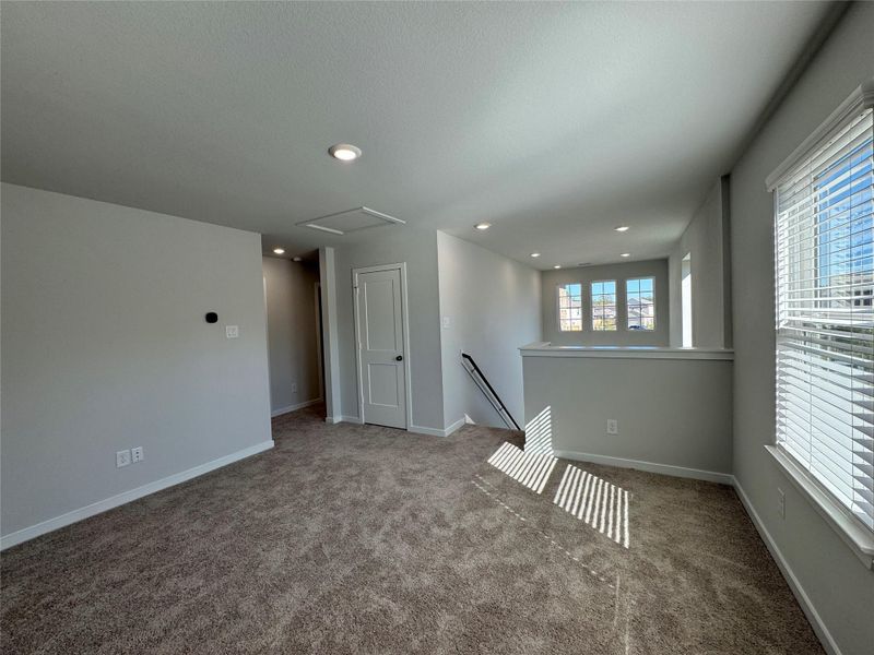 Bright, carpeted upstairs game room featuring ample natural light from multiple windows, recessed lighting, and a neutral color palette. The open layout provides flexible use as a game room, media space, or secondary living area. Bright, carpeted upstairs game room featuring ample natural light from multiple windows, recessed lighting, and a neutral color palette. The open layout provides flexible use as a game room, media space, or secondary living area.