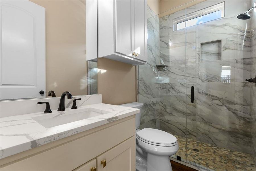 Bathroom featuring vanity, a shower with door, and toilet