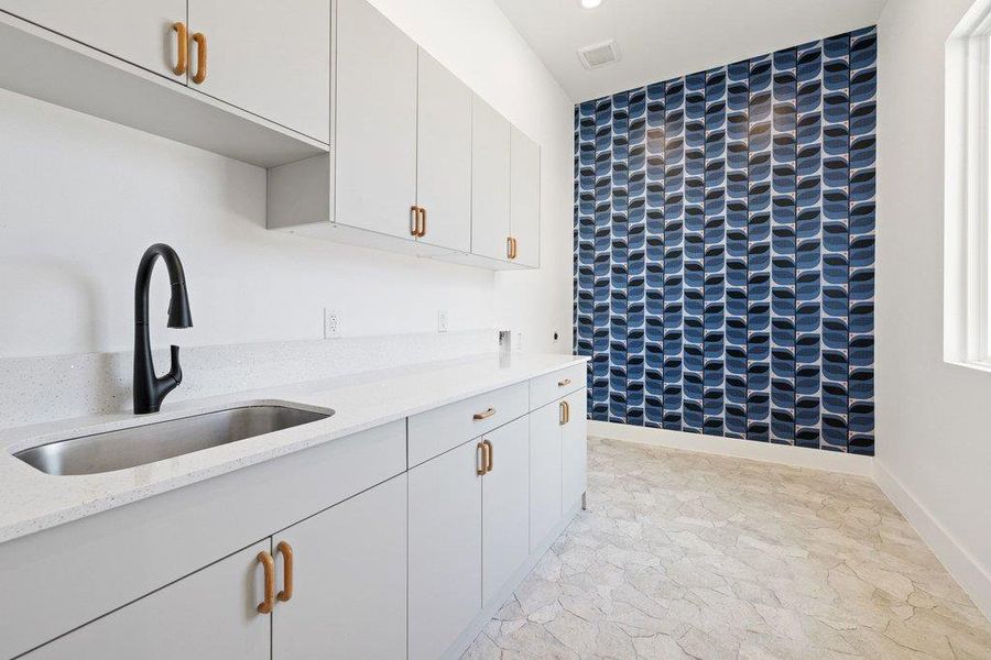 Kitchen with an accent wall, light stone countertops, white cabinetry, and recessed lighting