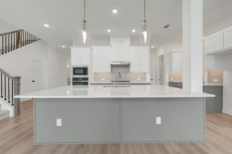 Modern kitchen island featuring a light-toned countertop and contrasting gray paneling Modern kitchen island featuring a light-toned countertop and contrasting gray paneling