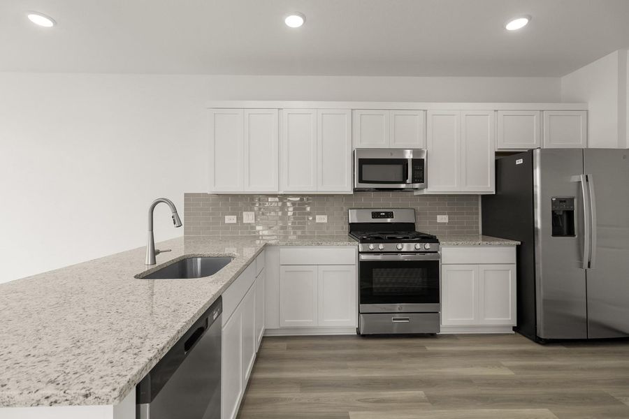 Kitchen featuring white cabinetry, stainless steel appliances, light stone counters, light wood-style flooring, and recessed lighting