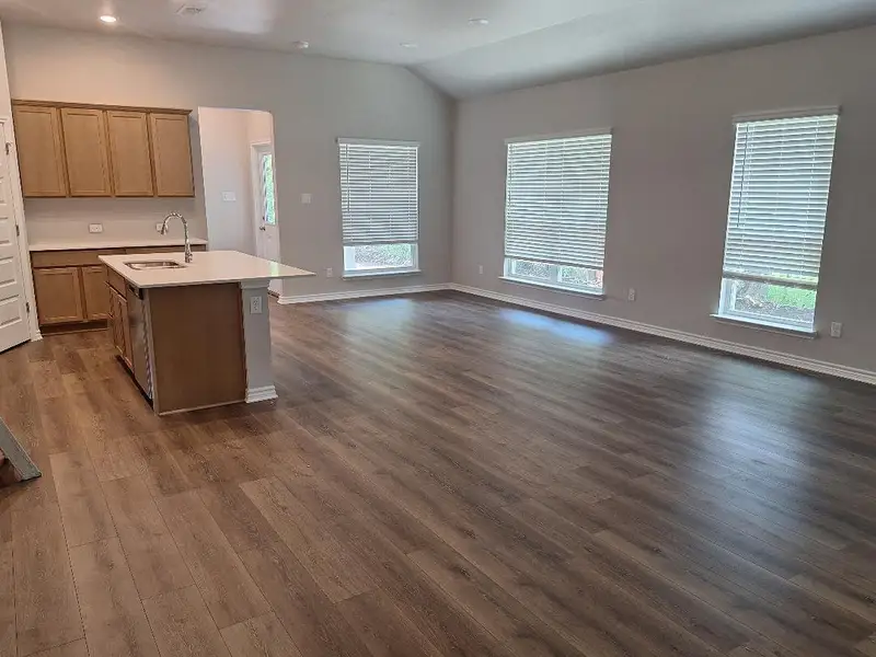Kitchen with dark wood-type flooring, light countertops, open floor plan, plenty of natural light, and vaulted ceiling