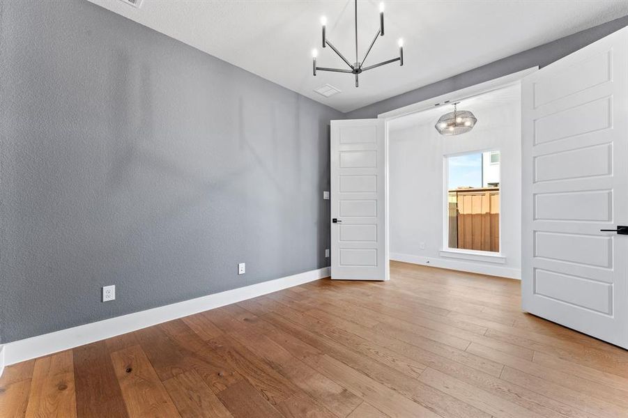 Spare room with a notable chandelier and light wood-type flooring