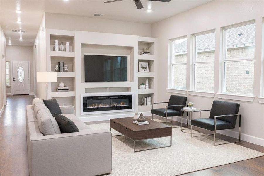 Living room with wood finished floors, built in features, a glass covered fireplace, ceiling fan, and recessed lighting Living room with wood finished floors, built in features, a glass covered fireplace, ceiling fan, and recessed lighting