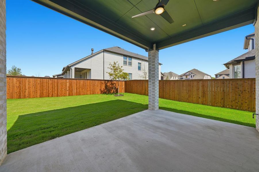 Fenced backyard with a ceiling fan, a patio area, and a residential view Fenced backyard with a ceiling fan, a patio area, and a residential view