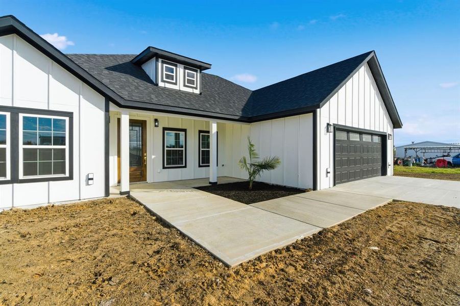Modern inspired farmhouse featuring a shingled roof, board and batten siding, a porch, concrete driveway, and an attached garage