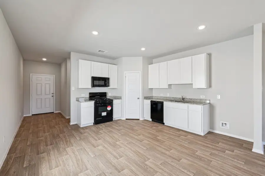 Image of a kitchen with white cabinets, a corner pantry, and black appliances