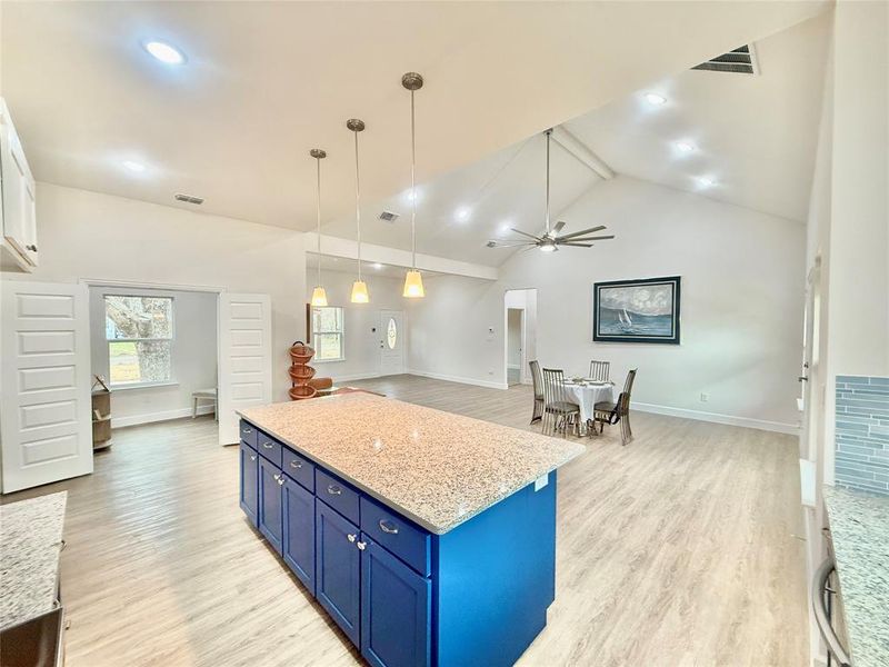 Kitchen featuring hanging light fixtures, blue cabinetry, high vaulted ceiling, and light hardwood / wood-style flooring