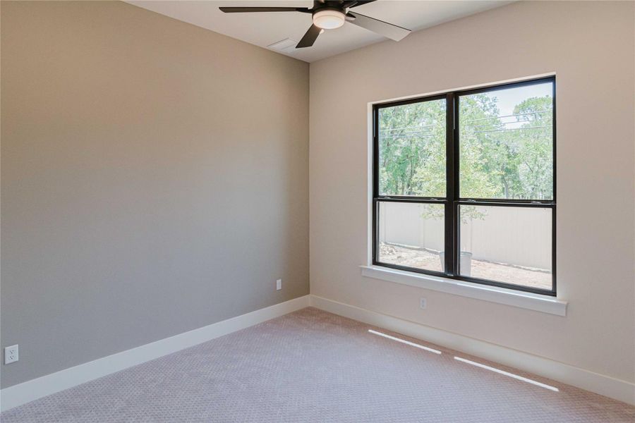 Carpeted spare room featuring baseboards and a ceiling fan