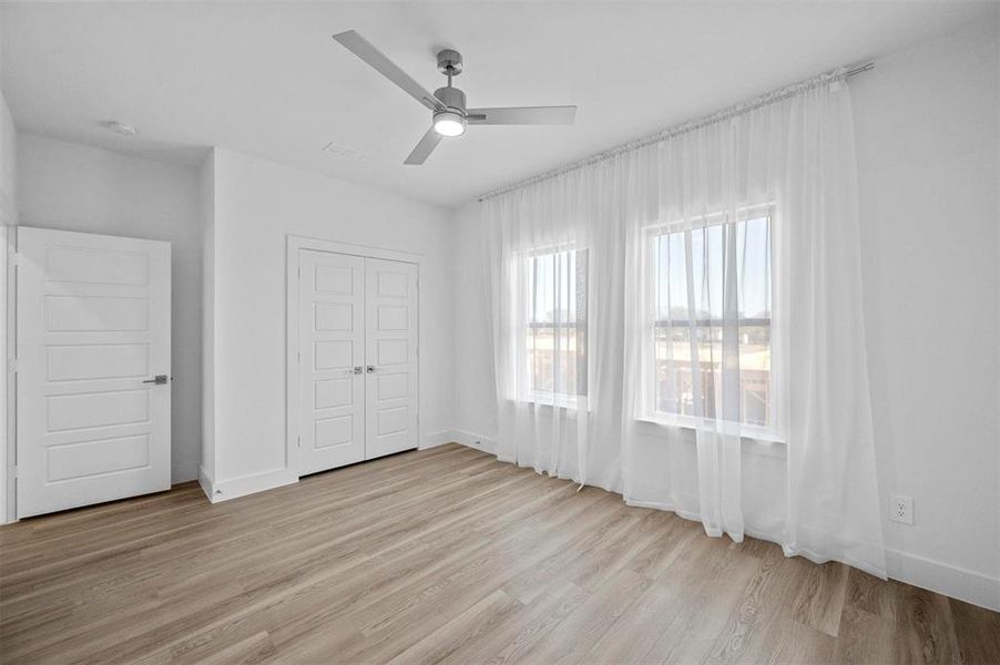 Unfurnished bedroom featuring ceiling fan, visible vents, baseboards, a closet, and light wood finished floors