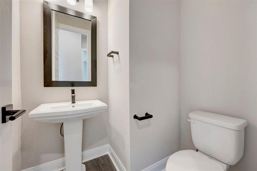 Pedestal sink with dark-framed mirror and wall-mounted light fixture