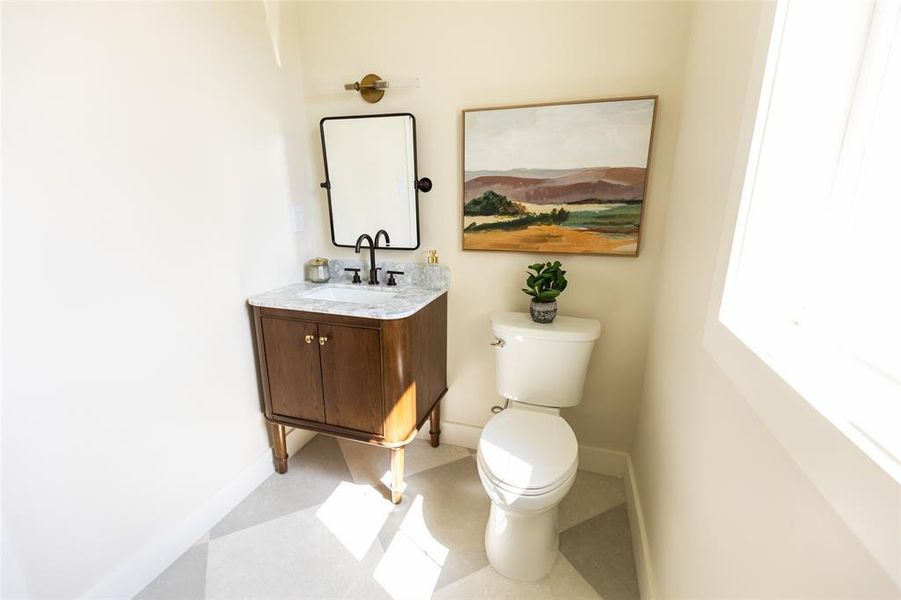 Bathroom featuring a dark wood vanity with a white countertop, a rectangular mirror, and matte black fixtures