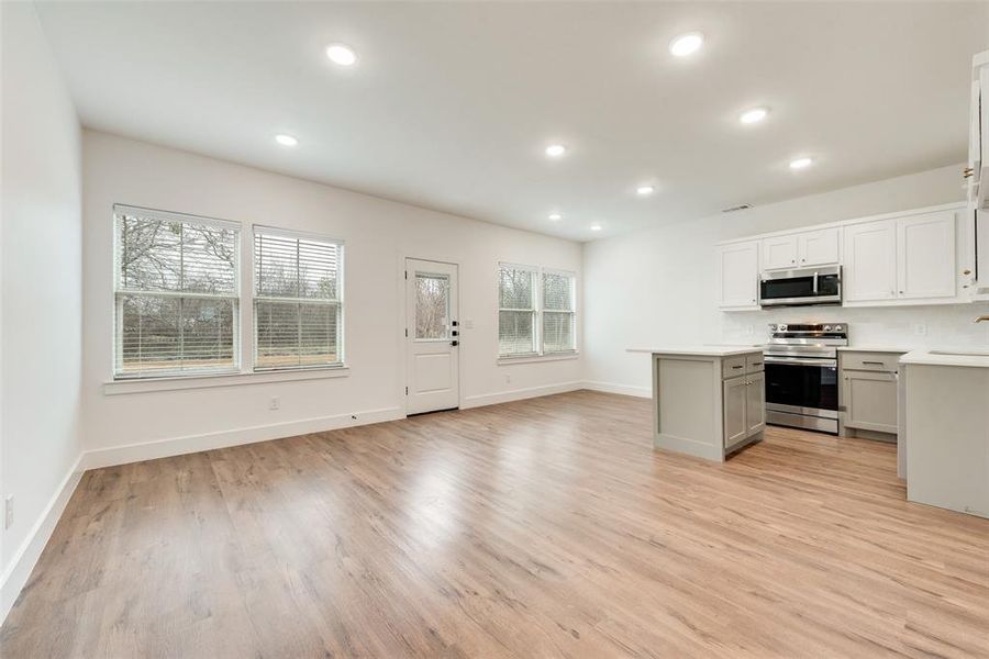 Kitchen with sink, light hardwood / wood-style flooring, white cabinets, and appliances with stainless steel finishes