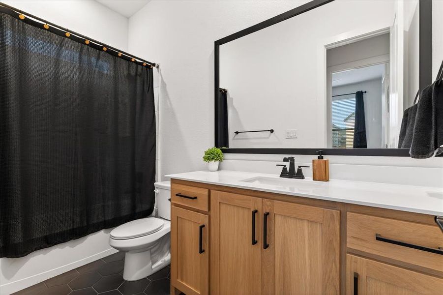 Full bathroom featuring vanity, dark tile patterned flooring, and shower / bath combo Full bathroom featuring vanity, dark tile patterned flooring, and shower / bath combo