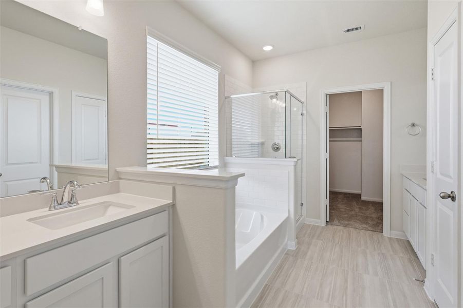 Spa inspired primary bathroom showcasing dual sinks, a soaking tub, and a separate shower, all designed to provide both comfort and functionality for everyday living. Spa inspired primary bathroom showcasing dual sinks, a soaking tub, and a separate shower, all designed to provide both comfort and functionality for everyday living.