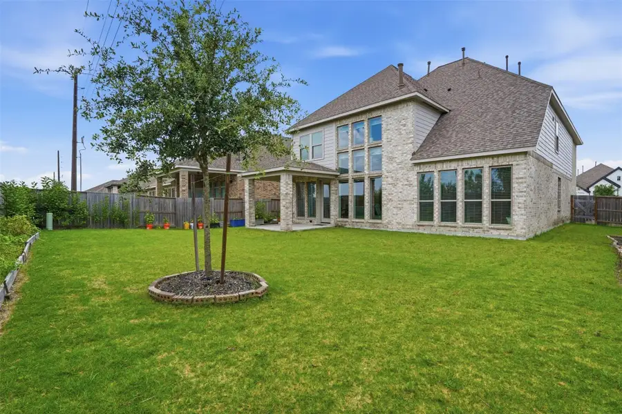 A spacious backyard features a well-maintained lawn with a small tree. The house showcases large windows and light-colored brick, offering a bright, inviting atmosphere. Ideal for outdoor activities and relaxation. A spacious backyard features a well-maintained lawn with a small tree. The house showcases large windows and light-colored brick, offering a bright, inviting atmosphere. Ideal for outdoor activities and relaxation.