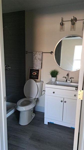 Bathroom with toilet, a shower, vanity, and wood-type flooring