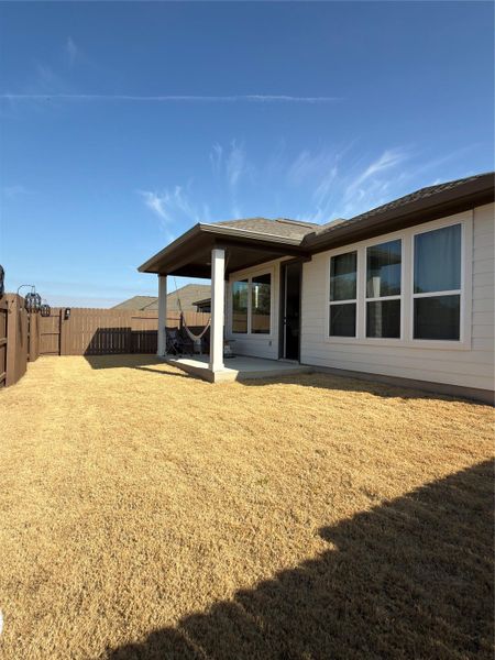 Private backyard with a covered patio, featuring a concrete surface and substantial support columns