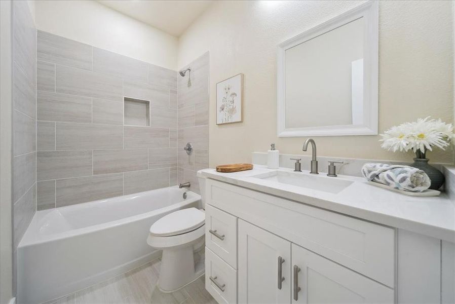 Full bathroom featuring tiled shower / bath combo, toilet, and vanity