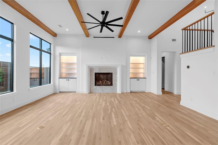 Unfurnished living room featuring built in shelves, a ceiling fan, light wood-type flooring, a premium fireplace, and recessed lighting Unfurnished living room featuring built in shelves, a ceiling fan, light wood-type flooring, a premium fireplace, and recessed lighting