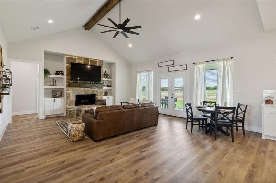 Spacious living area featuring vaulted ceilings with an exposed wood beam, recessed lighting, and wood-finish flooring
