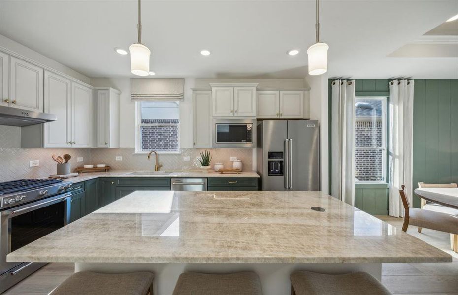 Large island overlooking gathering room and dining areas *Model Representation*