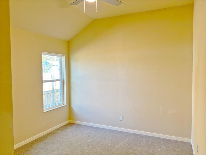 Carpeted empty room featuring lofted ceiling and baseboards