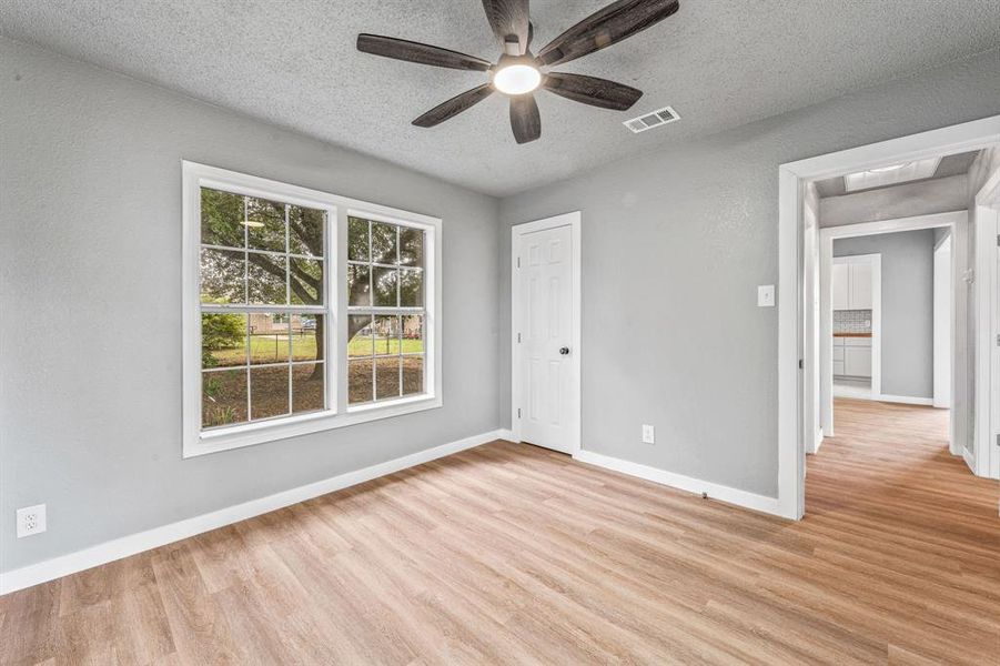 Unfurnished bedroom with a textured ceiling, light wood-style flooring, and a ceiling fan Unfurnished bedroom with a textured ceiling, light wood-style flooring, and a ceiling fan