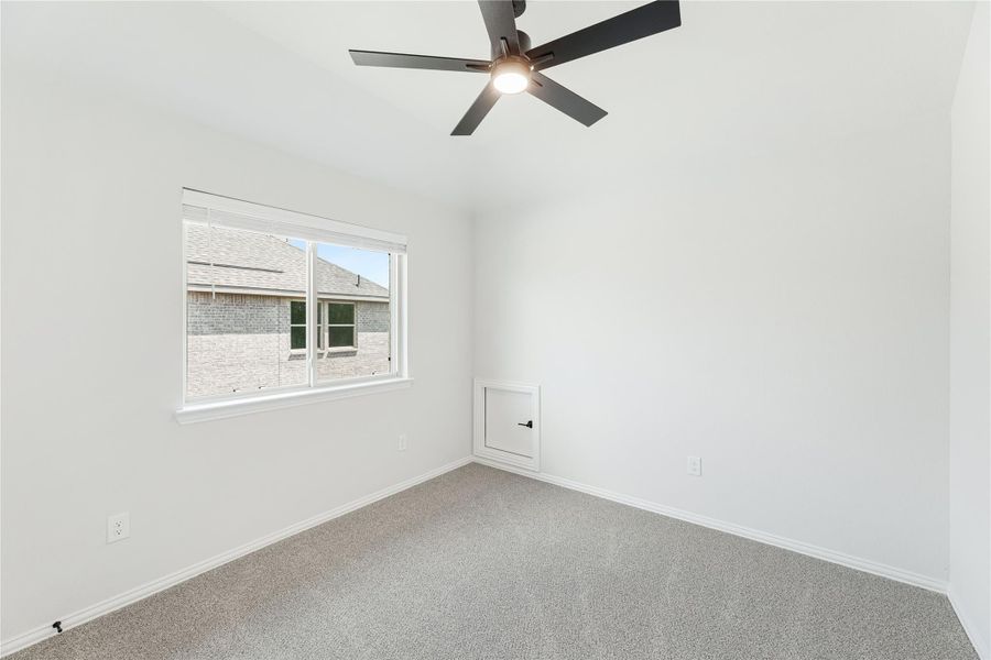 Empty bedroom with gray carpet, ceiling fan, and single window with white walls