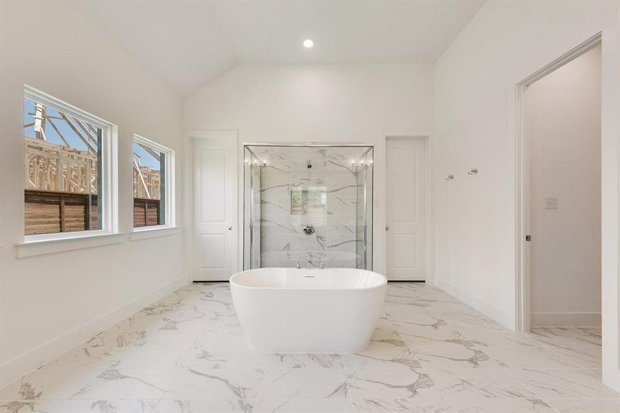 Full bath featuring a marble finish shower, a freestanding tub, light marble finish flooring, vaulted ceiling, and recessed lighting Full bath featuring a marble finish shower, a freestanding tub, light marble finish flooring, vaulted ceiling, and recessed lighting