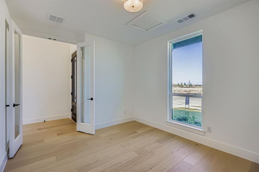 Unfurnished bedroom featuring light wood finished floors and attic access