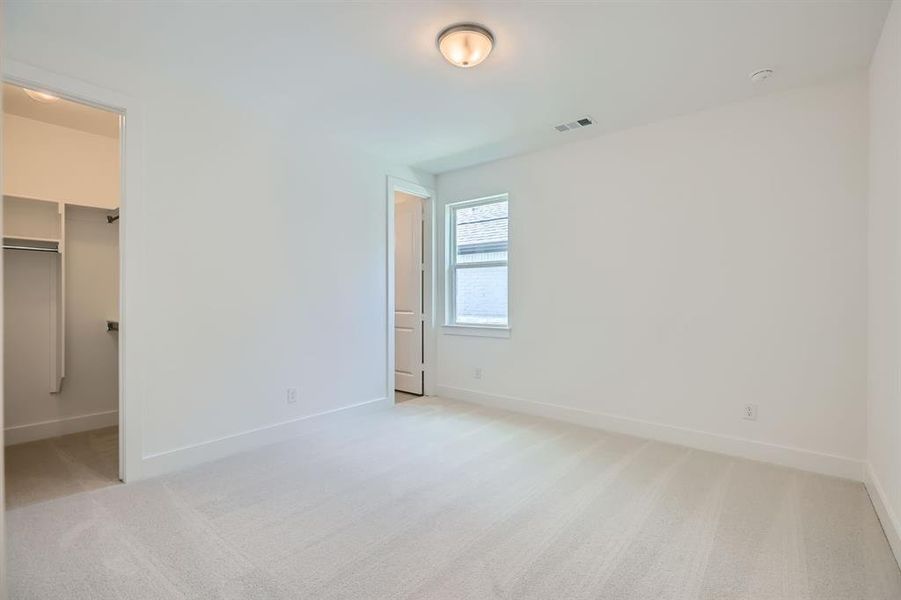 Unfurnished bedroom with light colored carpet, baseboards, and a spacious closet