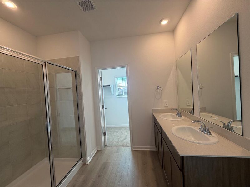 Full bathroom featuring light wood finished floors, a stall shower, double vanity, and recessed lighting