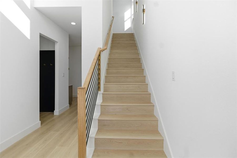 Stairway featuring wood finished floors and recessed lighting