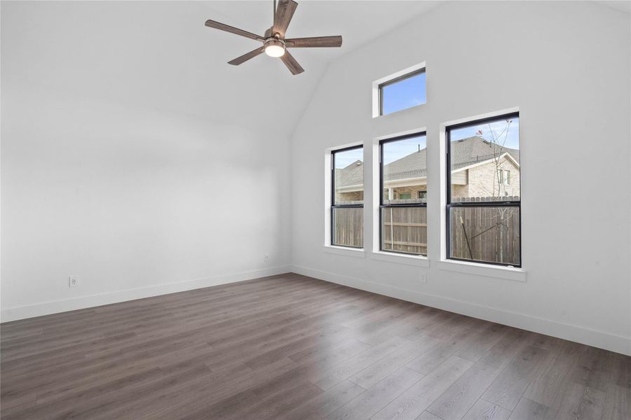 Relax and unwind after a long day in this impressive primary suite! This generously sized room offers laminate flooring, neutral-toned paint, high ceilings with a ceiling fan, and large windows for added comfort and tranquility.