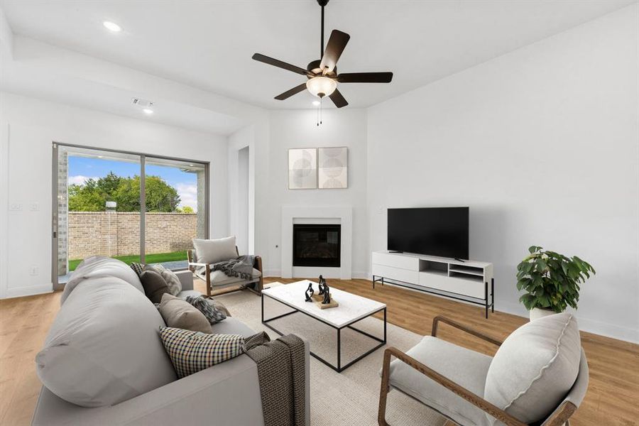 Living room with light wood-type flooring, a ceiling fan, a glass covered fireplace, and recessed lighting Living room with light wood-type flooring, a ceiling fan, a glass covered fireplace, and recessed lighting
