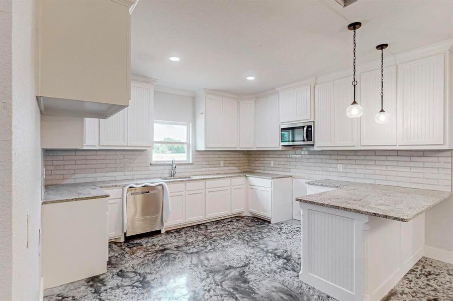 Kitchen featuring pendant lighting, sink, tasteful backsplash, white cabinetry, and stainless steel appliances